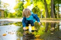 Adorable toddler boy wearing yellow rubber boots playing in a a puddle on sunny autumn day in city park. Child exploring nature. Royalty Free Stock Photo