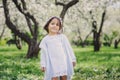 Adorable toddler child girl in light blue dressy outfit walking and playing in blooming spring garden