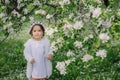 Adorable toddler child girl in light blue dressy outfit walking and playing in blooming spring garden