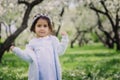 Adorable toddler child girl in light blue dressy outfit walking and playing in blooming spring garden