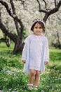 Adorable toddler child girl in light blue dressy outfit walking and playing in blooming spring garden