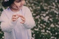 Adorable toddler child girl in light blue dressy outfit walking and playing in blooming spring garden