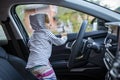 Adorable toddler child plays driving on drivers seat of modern premium car