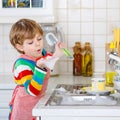 Adorable toddler child washing dishes in domestic kitchen. Royalty Free Stock Photo