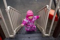 Adorable toddler climbs the stairs on the playground. toddler baby dressed in a snowsuit. autumn or winter, cold season