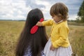 Adorable toddler girl combing her mom`s hair outdoors outdoors on a sunny day Royalty Free Stock Photo