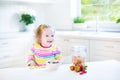 Adorable toddler girl with curly hair having breakfast Royalty Free Stock Photo