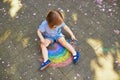 Adorable toddler girl drawing rainbow with colorful chalks on asphalt Royalty Free Stock Photo