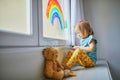 Adorable toddler girl drawing rainbow on window glass Royalty Free Stock Photo