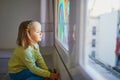 Adorable toddler girl drawing rainbow on window glass Royalty Free Stock Photo