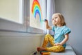 Adorable toddler girl drawing rainbow on window glass Royalty Free Stock Photo