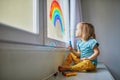 Adorable toddler girl drawing rainbow on window glass Royalty Free Stock Photo