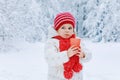 Adorable toddler girl drinking hot chocolate in winter forest. Happy healthy child with cup of steaming cocoa or tea