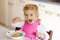 Adorable toddler girl eating healthy vegetable meal with potatoes and carrots soup for lunch. Cute happy baby child Royalty Free Stock Photo