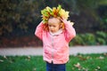 Adorable toddler girl in fallen leaves wreath in autumn park