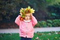 Adorable toddler girl in fallen leaves wreath in autumn park