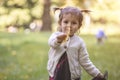 Adorable toddler girl holds out an autumn yellow maple leaf into the camera.. Royalty Free Stock Photo