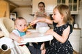 Adorable toddler girl at home feeding her baby brother. Royalty Free Stock Photo