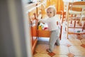 Adorable toddler girl at home, opening the drawer in the kitchen