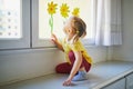 Adorable toddler girl looking at yellow flowers painted on window glass Royalty Free Stock Photo