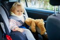 Adorable toddler girl in modern car seat with her favorite stuffed toy Royalty Free Stock Photo