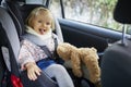 Adorable toddler girl in modern car seat with her favorite stuffed toy Royalty Free Stock Photo