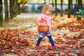 Adorable toddler girl picking chestnuts in Tuileries garden in Paris, France