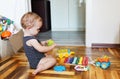 Adorable toddler girl playing with colorful toys sitting on a floor in a sunny bedroom Royalty Free Stock Photo