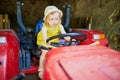Adorable toddler girl playing on old red tractor on Gally farm near Paris, France