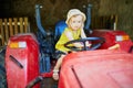 Adorable toddler girl playing on old red tractor on Gally farm near Paris, France