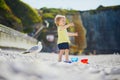 Adorable toddler girl playing with pebbles on the beach in Etretat Royalty Free Stock Photo