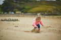 Adorable toddler girl playing with stones and building a town on the sand beach Royalty Free Stock Photo