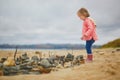 Adorable toddler girl playing with stones and building a town on the sand beach Royalty Free Stock Photo