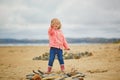 Adorable toddler girl playing with stones and building a town on the sand beach Royalty Free Stock Photo