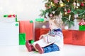 Adorable toddler girl reading book under Christmas tree Royalty Free Stock Photo