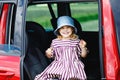 Adorable toddler girl sitting in car seat and looking out of the window on nature and traffic. Little kid traveling by Royalty Free Stock Photo