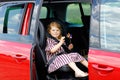 Adorable toddler girl sitting in car seat and looking out of the window on nature and traffic. Little kid traveling by Royalty Free Stock Photo