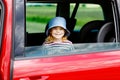 Adorable toddler girl sitting in car seat and looking out of the window on nature and traffic. Little kid traveling by Royalty Free Stock Photo