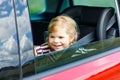 Adorable toddler girl sitting in car seat and looking out of the window on nature and traffic. Little kid traveling by Royalty Free Stock Photo