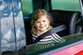 Adorable toddler girl sitting in car seat and looking out of the window on nature and traffic. Little kid traveling by Royalty Free Stock Photo