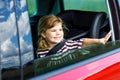 Adorable toddler girl sitting in car seat and looking out of the window on nature and traffic. Little kid traveling by Royalty Free Stock Photo