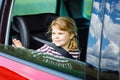 Adorable toddler girl sitting in car seat and looking out of the window on nature and traffic. Little kid traveling by Royalty Free Stock Photo