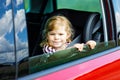 Adorable toddler girl sitting in car seat and looking out of the window on nature and traffic. Little kid traveling by Royalty Free Stock Photo