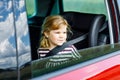 Adorable toddler girl sitting in car seat and looking out of the window on nature and traffic. Little kid traveling by Royalty Free Stock Photo