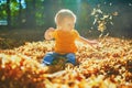 Adorable toddler girl sitting on the ground in large heap of fallen leaves Royalty Free Stock Photo