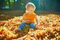 Adorable toddler girl sitting on the ground in large heap of fallen leaves Royalty Free Stock Photo