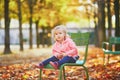 Adorable toddler girl sitting on traditional green chair in Tuileries garden in Paris