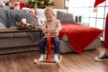 Adorable toddler playing on reindeer rocking by christmas tree at home