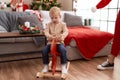 Adorable toddler playing on reindeer rocking by christmas tree at home