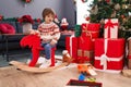 Adorable toddler playing on reindeer rocking by christmas tree at home